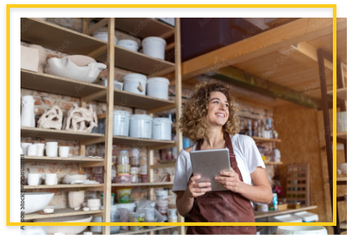 Woman in shop holding a tablet, smiling.